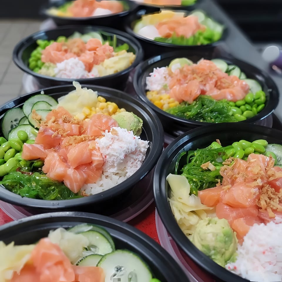 Multiple Oh Poke bowls filled with salmon, rice, edamame, seaweed, and other fresh toppings.